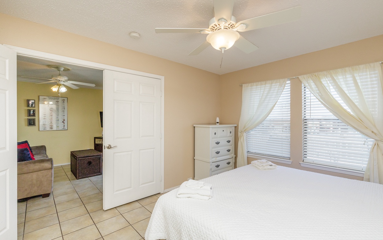 Relax in your bright, airy bedroom with crisp white linens and natural light streaming through elegant curtains.