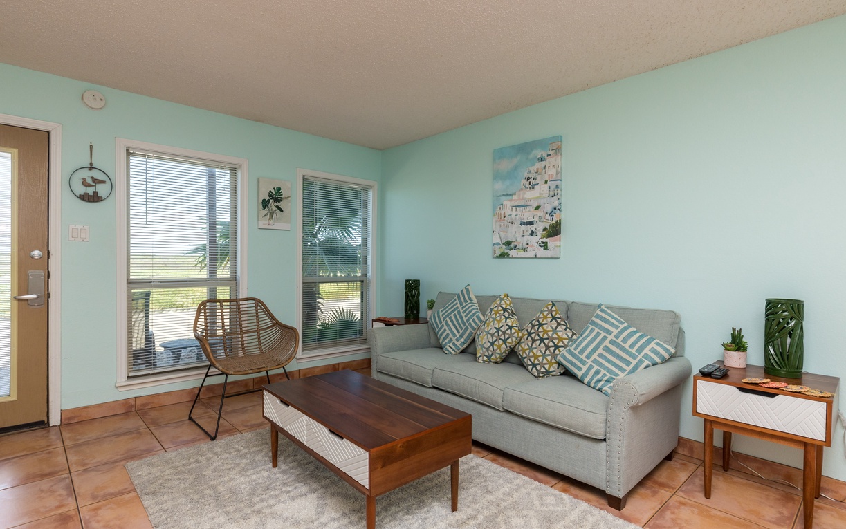 Relax in your bright living room with calming mint walls, plush gray sofa, and tropical touches that create the perfect coastal retreat.