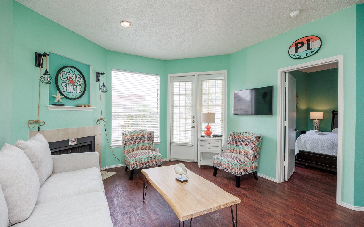 Relax in your bright, cheerful living space with vibrant turquoise walls, cozy seating, and natural light streaming through French doors.