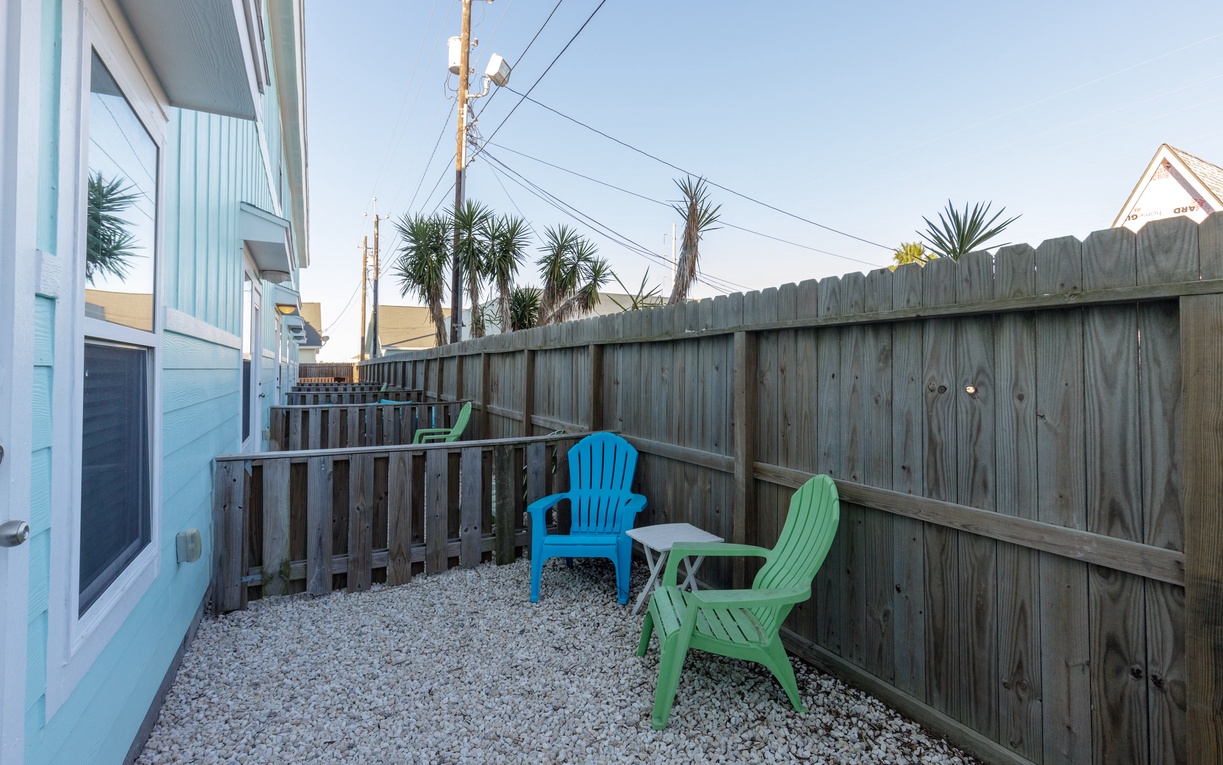 Your private patio offers a peaceful retreat with colorful seating surrounded by tropical palms and coastal charm.