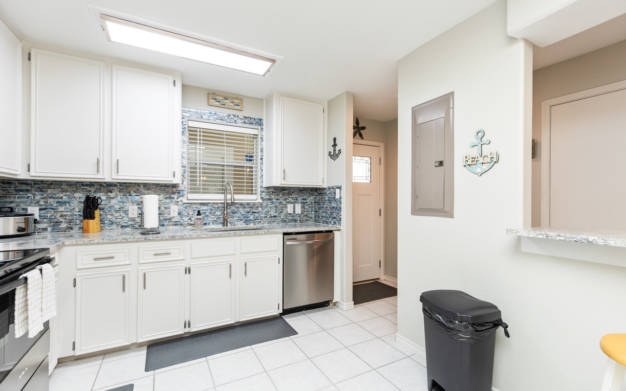 Your fully equipped kitchen awaits with modern appliances, elegant tile backsplash, and coastal charm perfect for preparing memorable meals together.