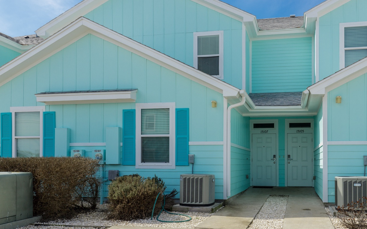 Charming turquoise beach cottage with white trim creates the perfect coastal getaway atmosphere for your vacation retreat.