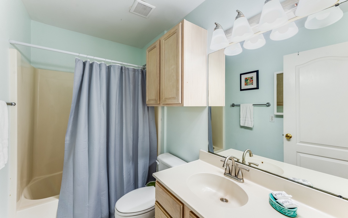 Step into your serene bathroom sanctuary with soothing mint walls, warm wood vanity, and fresh towels awaiting your arrival.