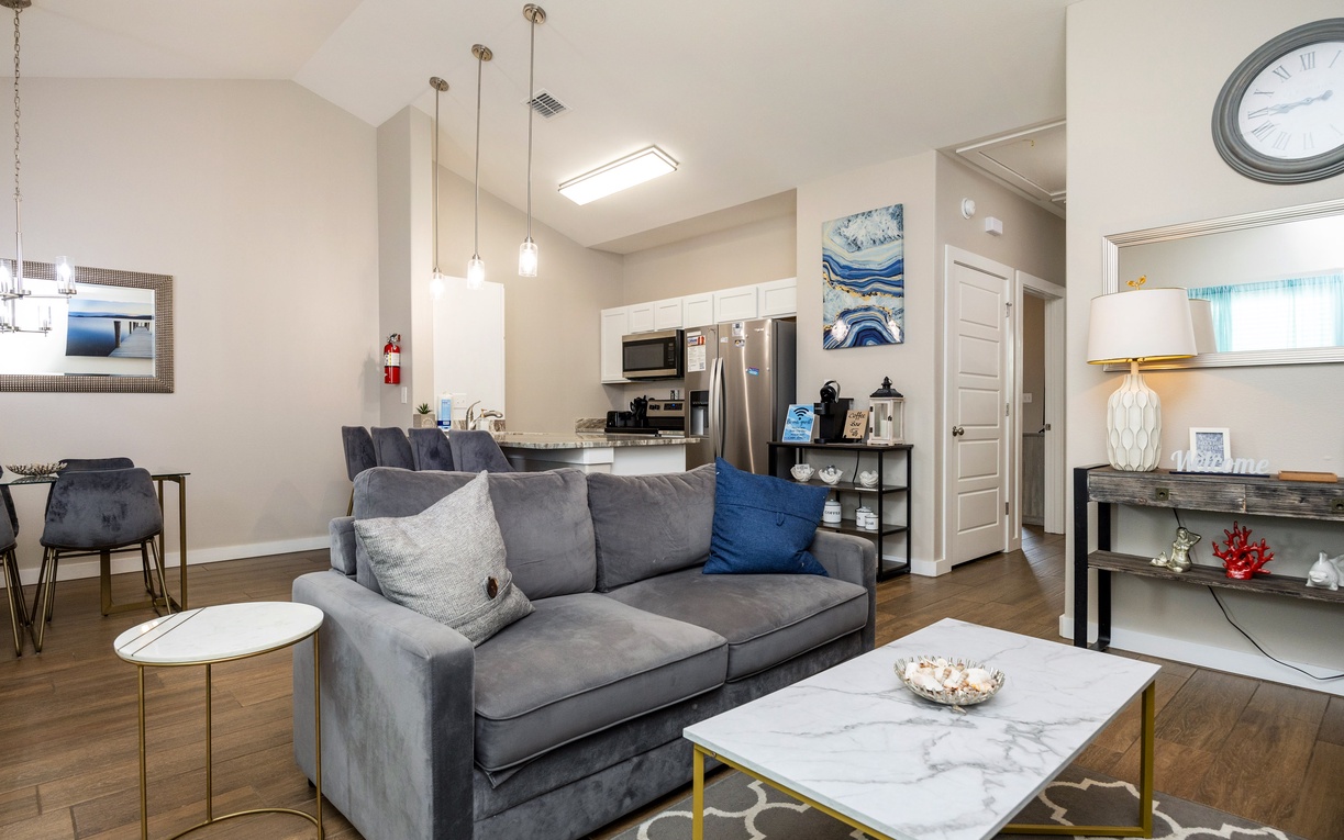 Sink into plush grey seating while admiring the open layout connecting your living space to a fully-equipped kitchen with stainless steel appliances.
