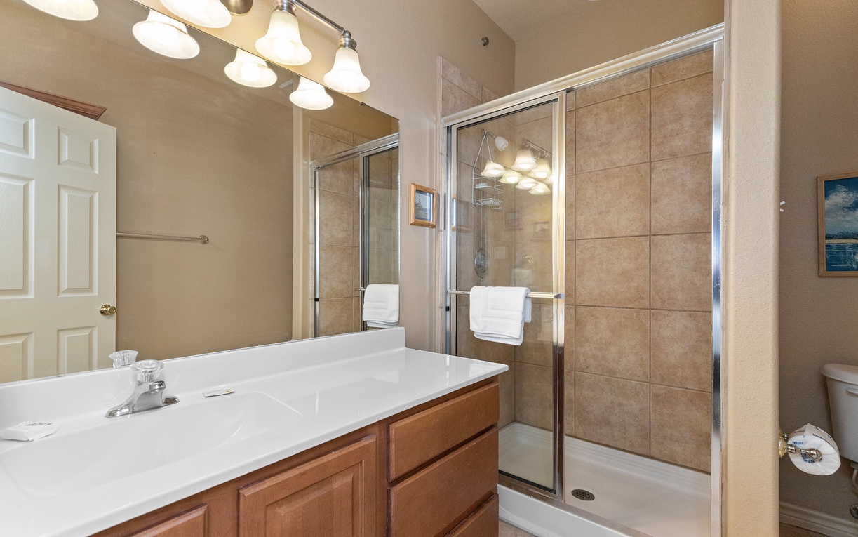 Refresh in your spacious bathroom with dual vanities, elegant lighting, and a tiled shower for a luxurious start to your day.