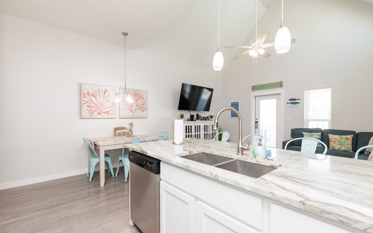 Cook and gather in your bright open kitchen with marble countertops, modern appliances, and coastal charm throughout this airy space.