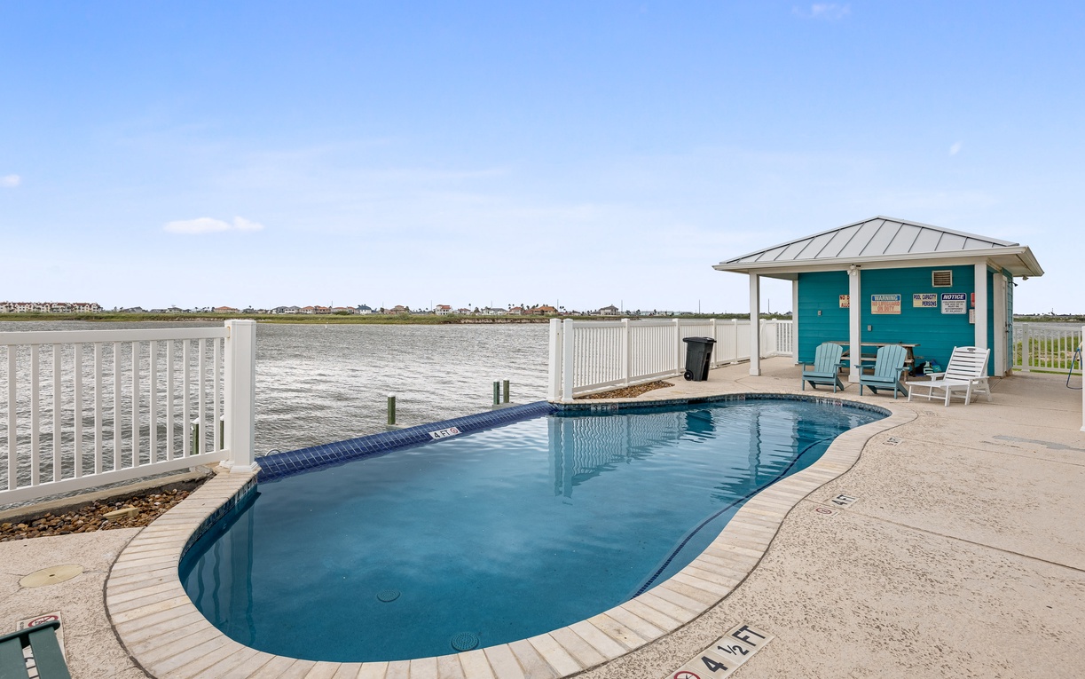 Waterfront pool deck with direct bay access and charming turquoise cabana for ultimate relaxation.