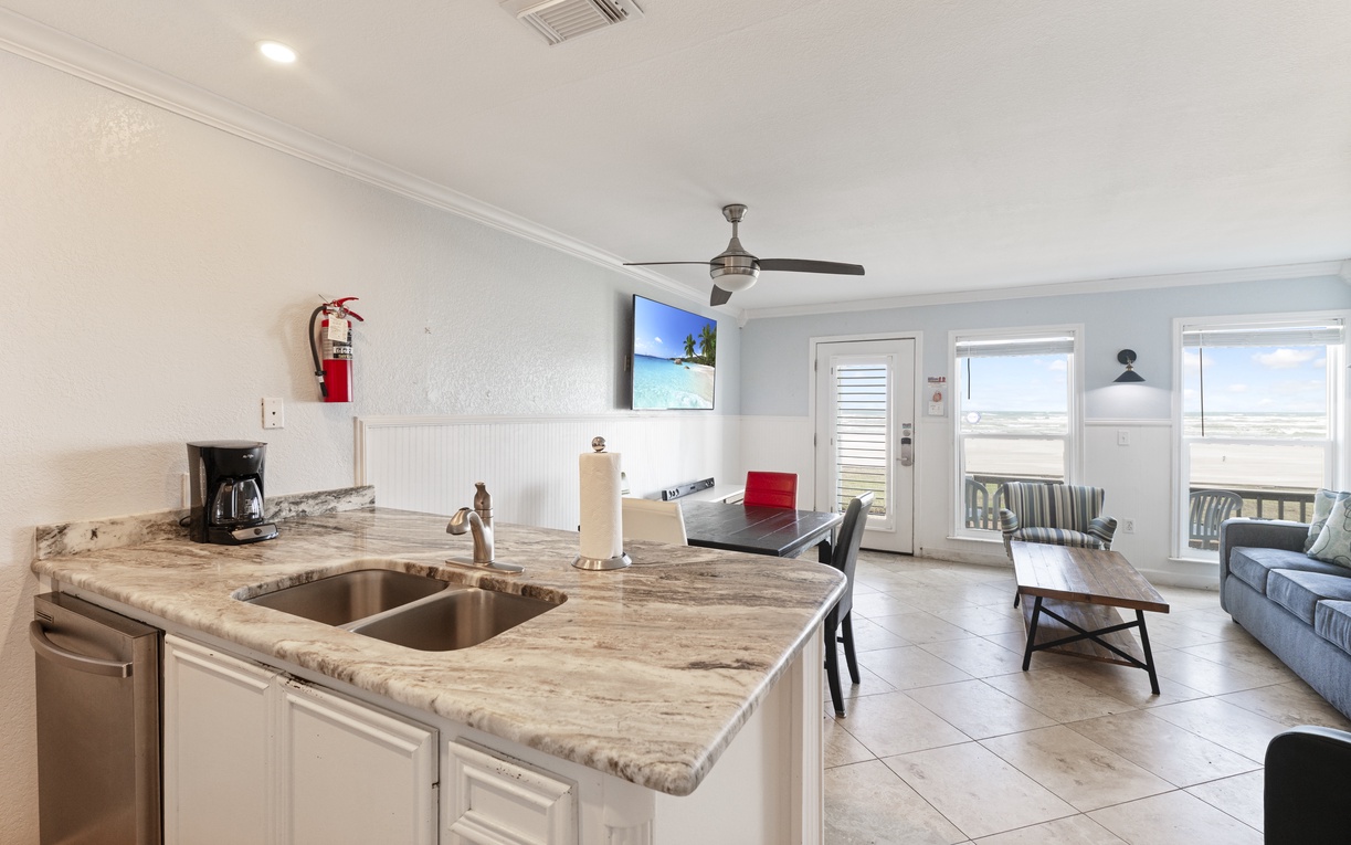 Your open kitchen flows seamlessly into the living area, perfect for preparing meals while enjoying ocean views through floor-to-ceiling windows.