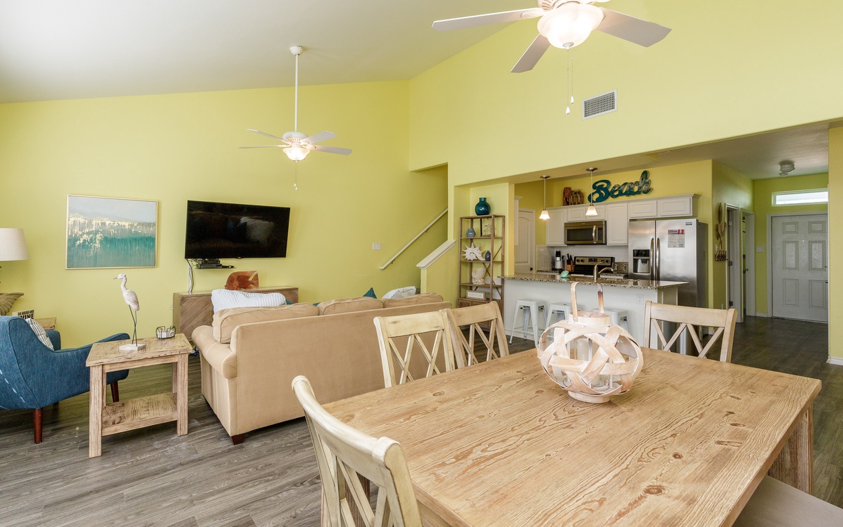 Relax in your bright, open-concept living space where coastal charm meets comfort. The dining table awaits your beach day stories.