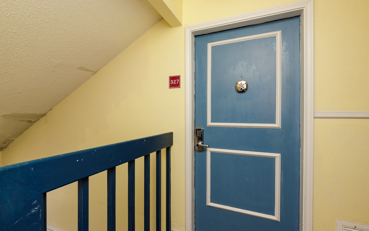 Your charming blue door welcomes you to room 327, perfectly positioned along the cozy stairway with its cheerful yellow walls.