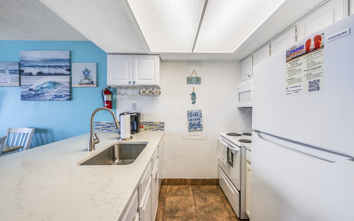 Clean, coastal kitchen with crisp counters, stainless sink, and everything you need to keep beach days fueled and easy.