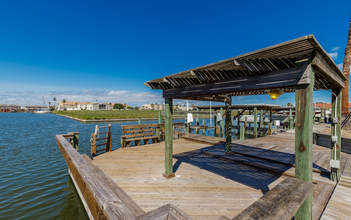 Waterfront dock with covered pavilion and boat slips, offering direct bay access for fishing and boating activities.