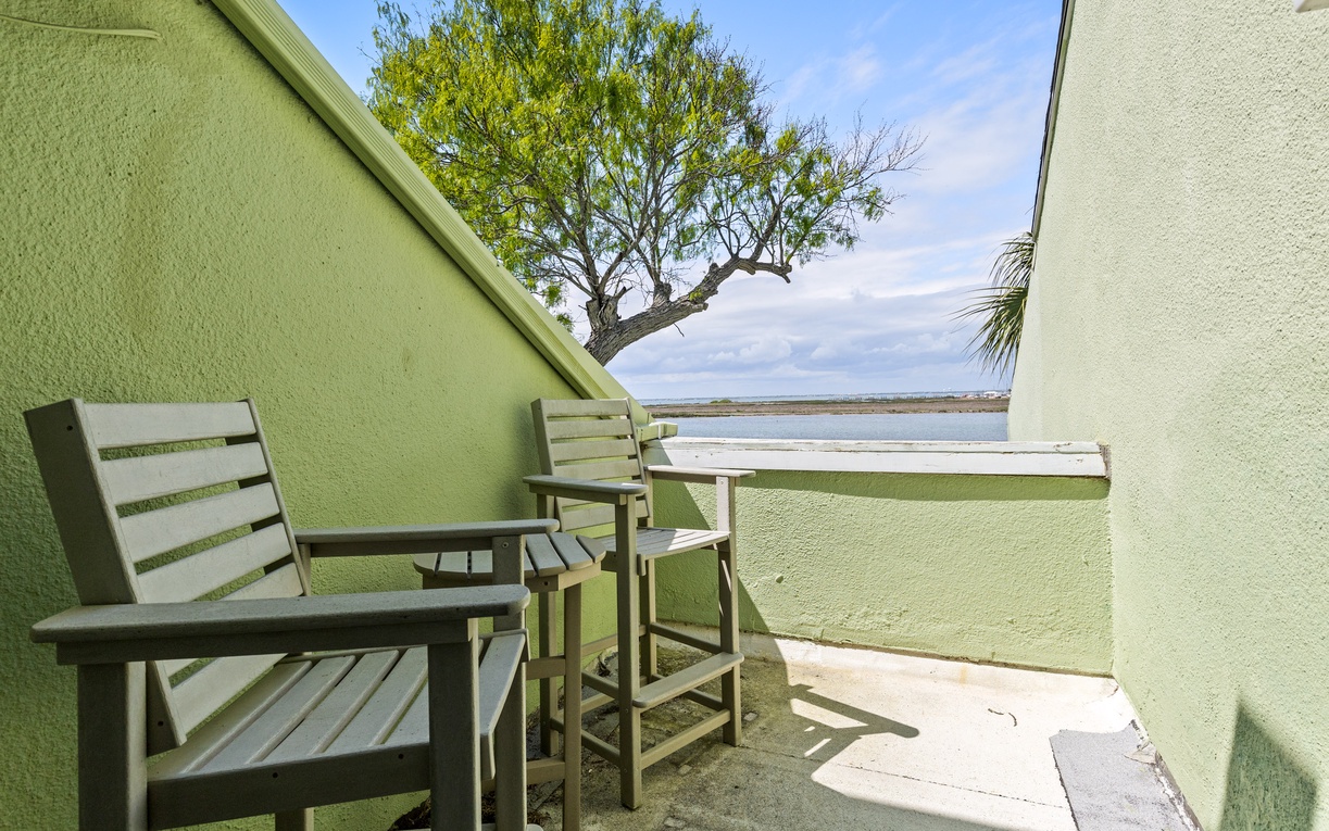 Step onto your private balcony where comfortable seating awaits and stunning water views stretch before you, framed by swaying palm trees.
