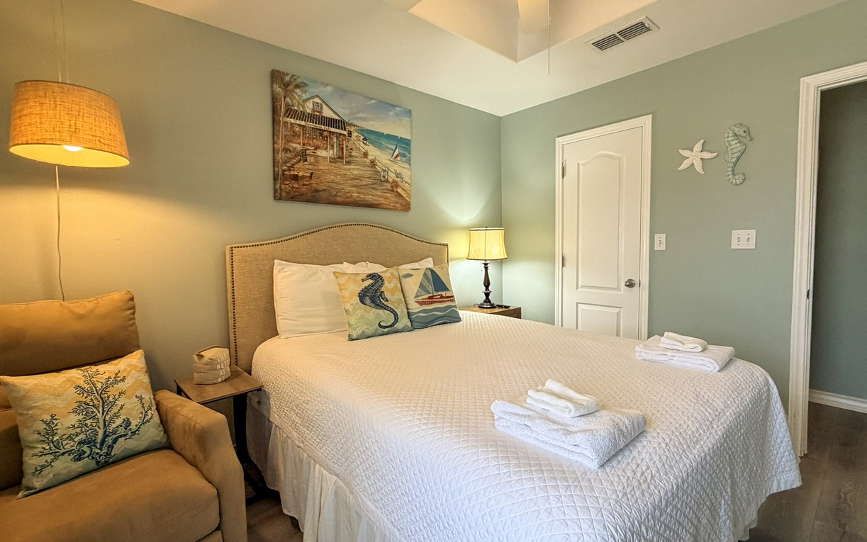 Drift off in this serene bedroom with calming seafoam walls, crisp linens, and beachy vibes from coastal artwork.