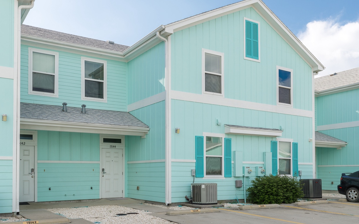 Bright turquoise beach-style townhome with covered parking and coastal charm in a peaceful residential setting.