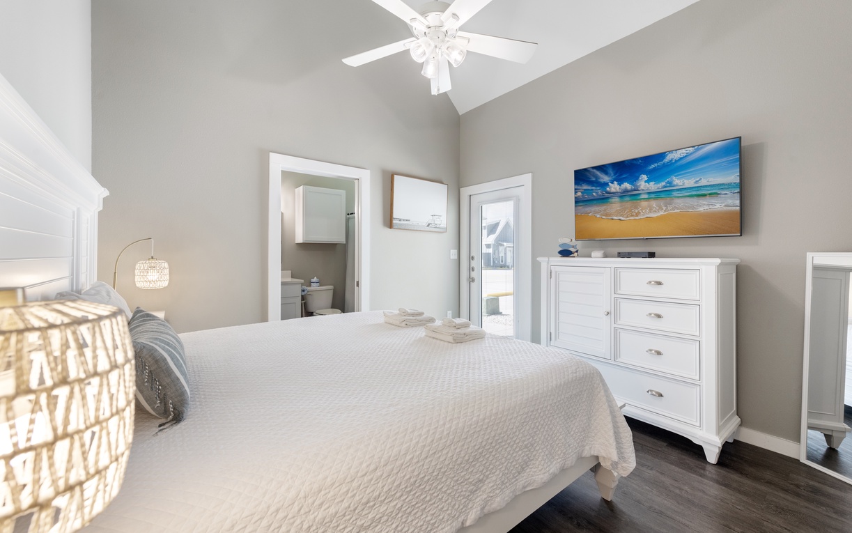 Your serene master suite features vaulted ceilings, coastal artwork, and crisp white linens for the perfect peaceful retreat.