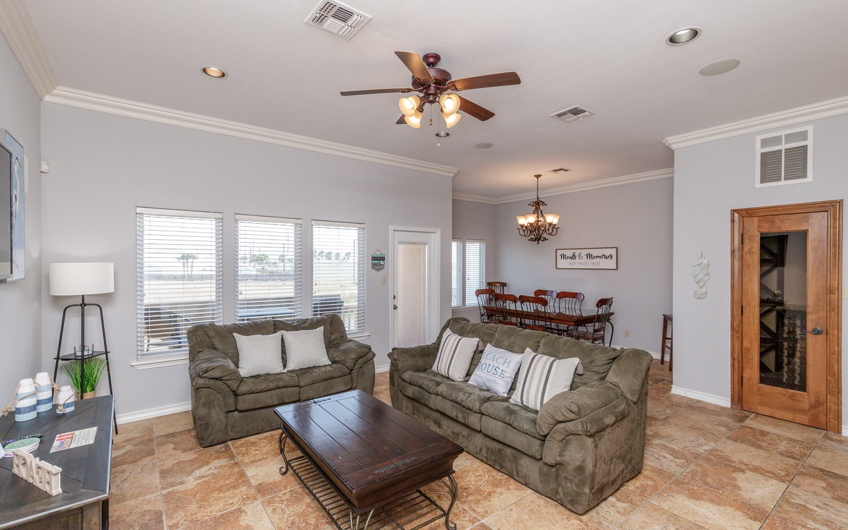 Settle into plush sofas in your bright living space where ceiling fans create gentle breezes and natural light flows through wide windows.