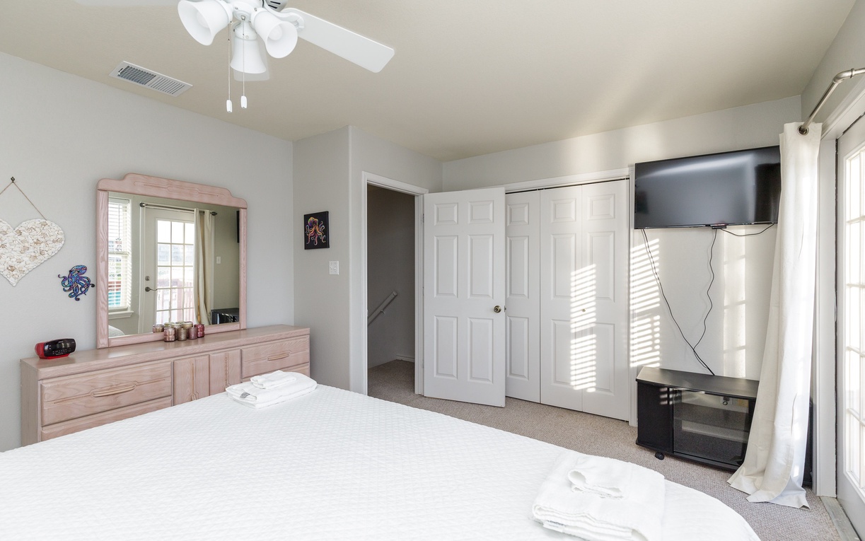 Your primary bedroom features a comfortable king size bed, ceiling fan, entertainment center, and ample storage with built-in closets.