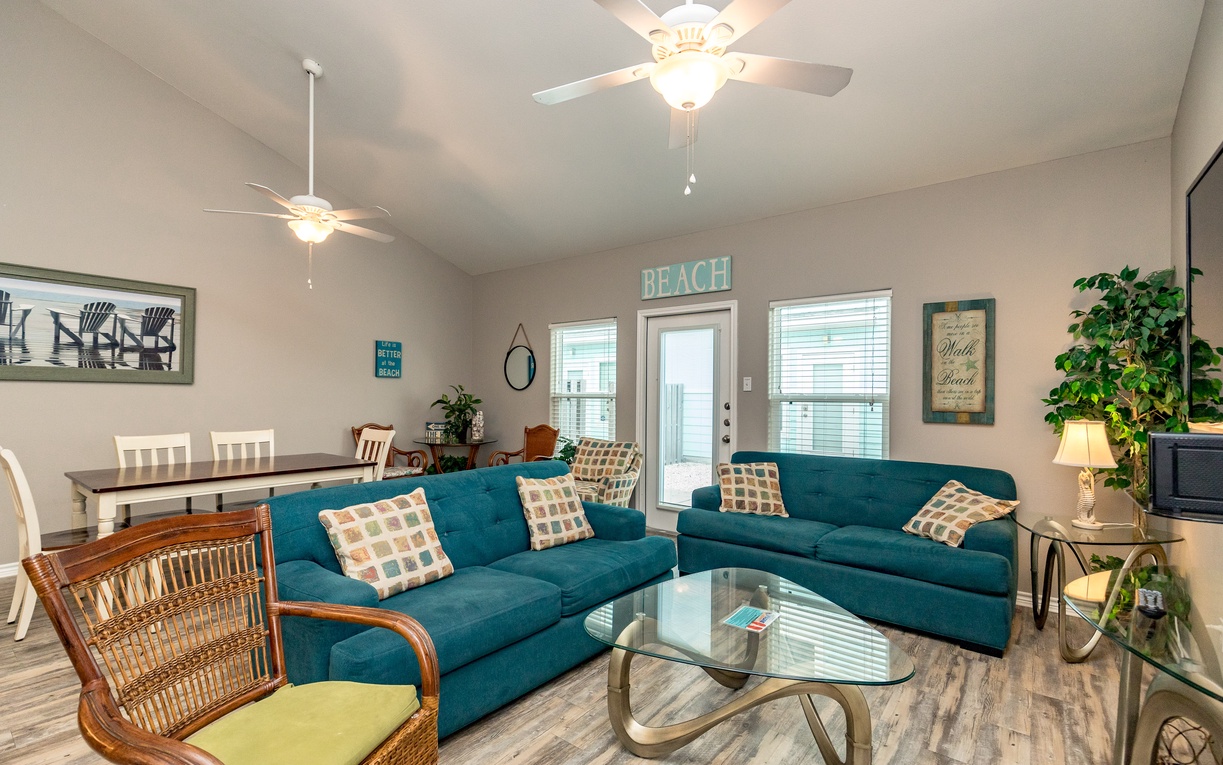 Sink into the plush teal sectional and feel instantly at home in this bright, beach-themed living space with coastal charm.