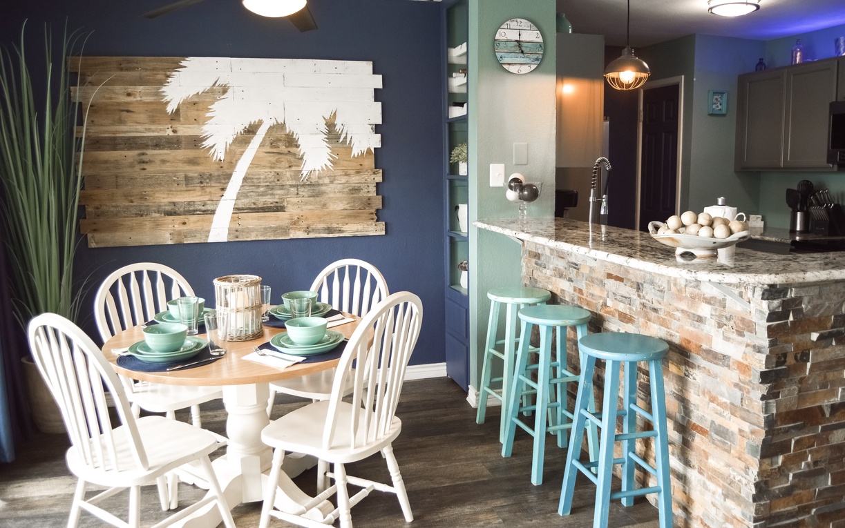 Your coastal-themed kitchen welcomes you with turquoise bar stools, palm tree art, and everything needed for memorable meals together.