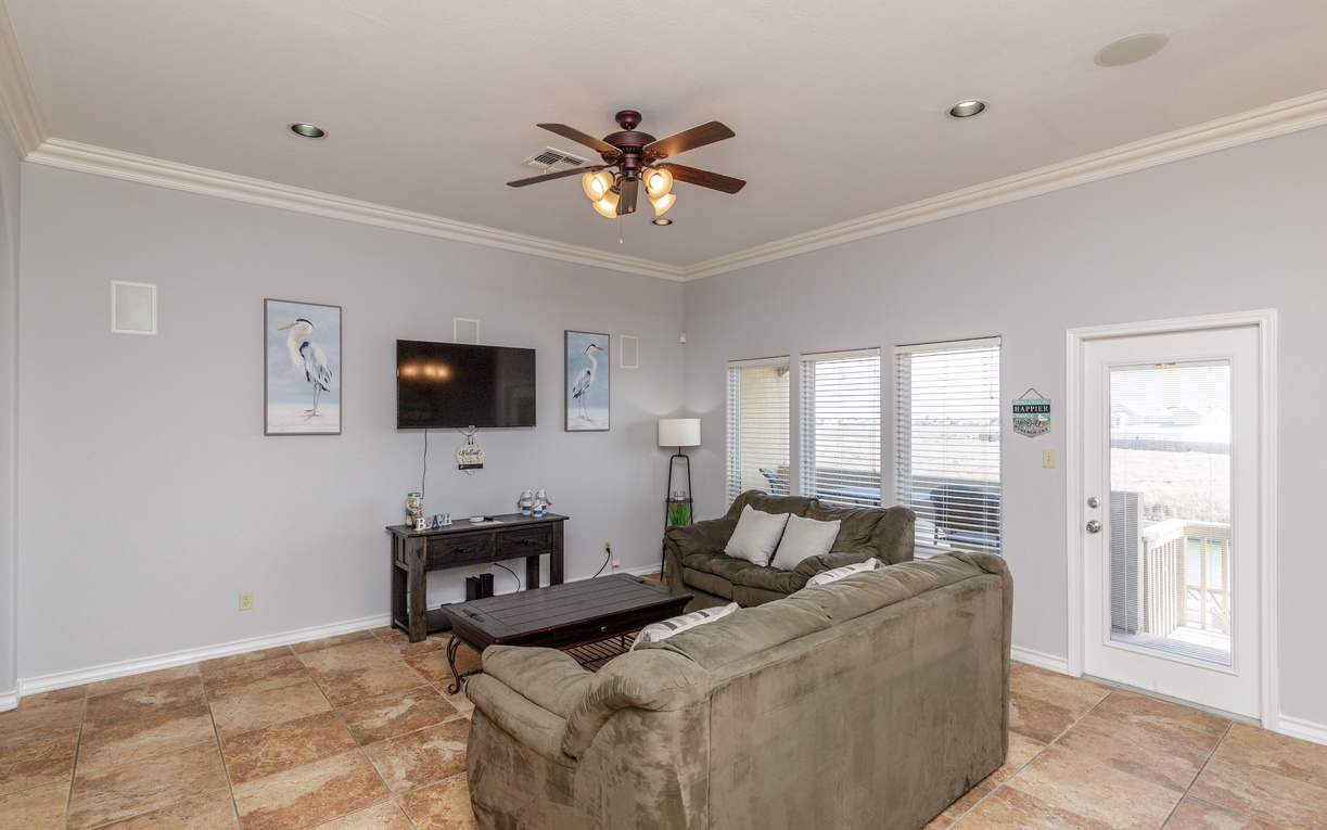 Relax in your comfortable living room with plush seating, ceiling fan, and modern entertainment setup for perfect downtime.