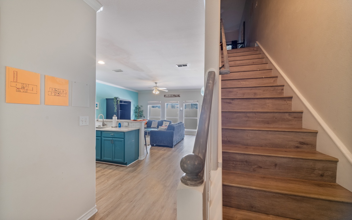 Your modern open-concept retreat features warm wood stairs leading to comfort, with a bright kitchen and cozy living space perfect for gathering.