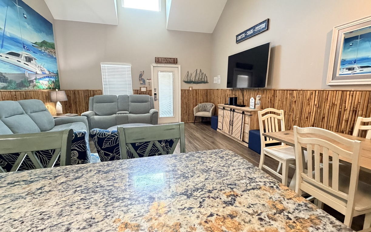 Relax in your nautical-themed gathering space featuring granite counters, bamboo accents, and comfortable seating with marine artwork adorning the walls.