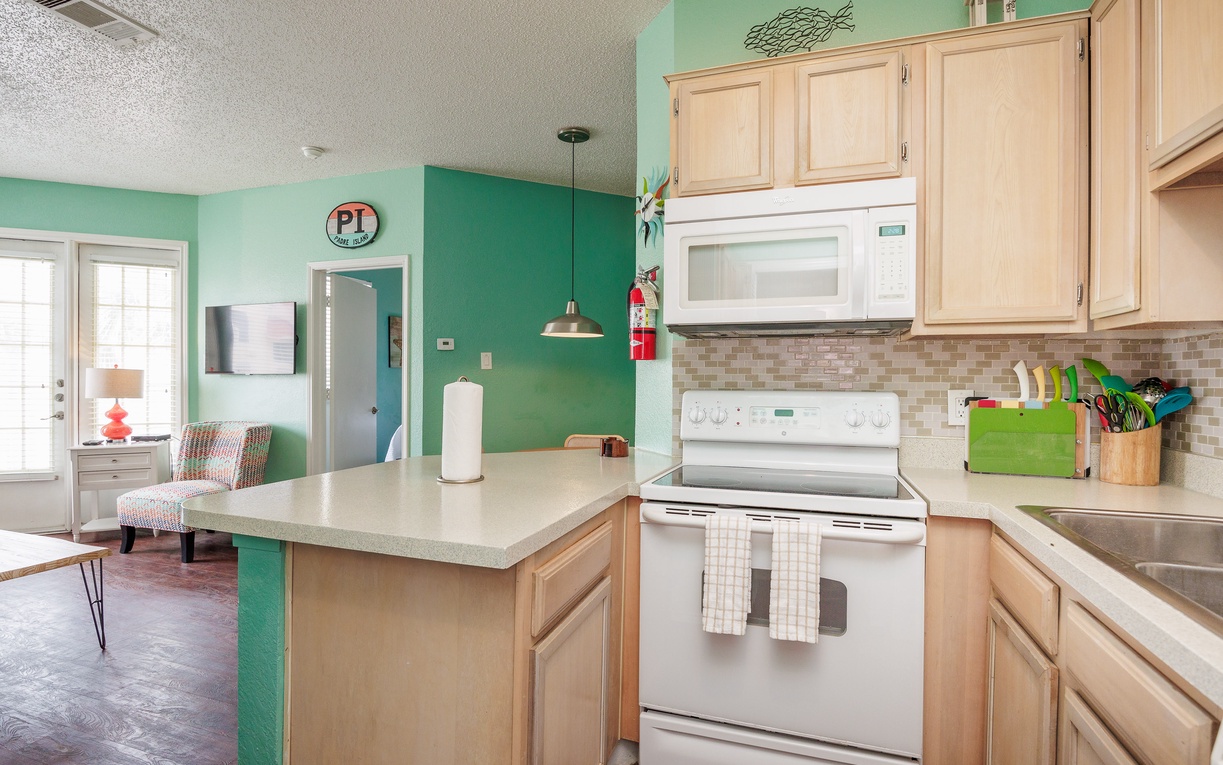 You'll love cooking in this vibrant kitchen with its cheerful mint walls, spacious island, and modern appliances—perfect for preparing meals together.