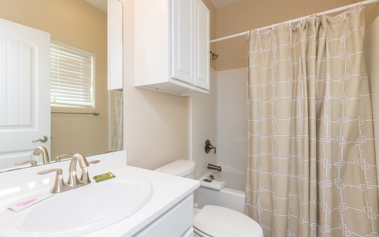 Step into your spotless bathroom featuring a spacious shower-tub combo, elegant white vanity, and thoughtful storage—your perfect morning routine awaits.