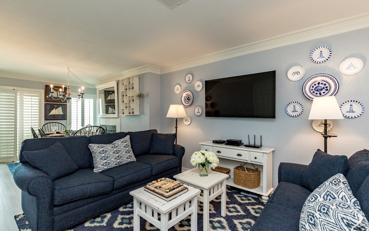 Settle into your stylish living room with plush navy sofas and charming nautical décor creating the perfect coastal retreat.