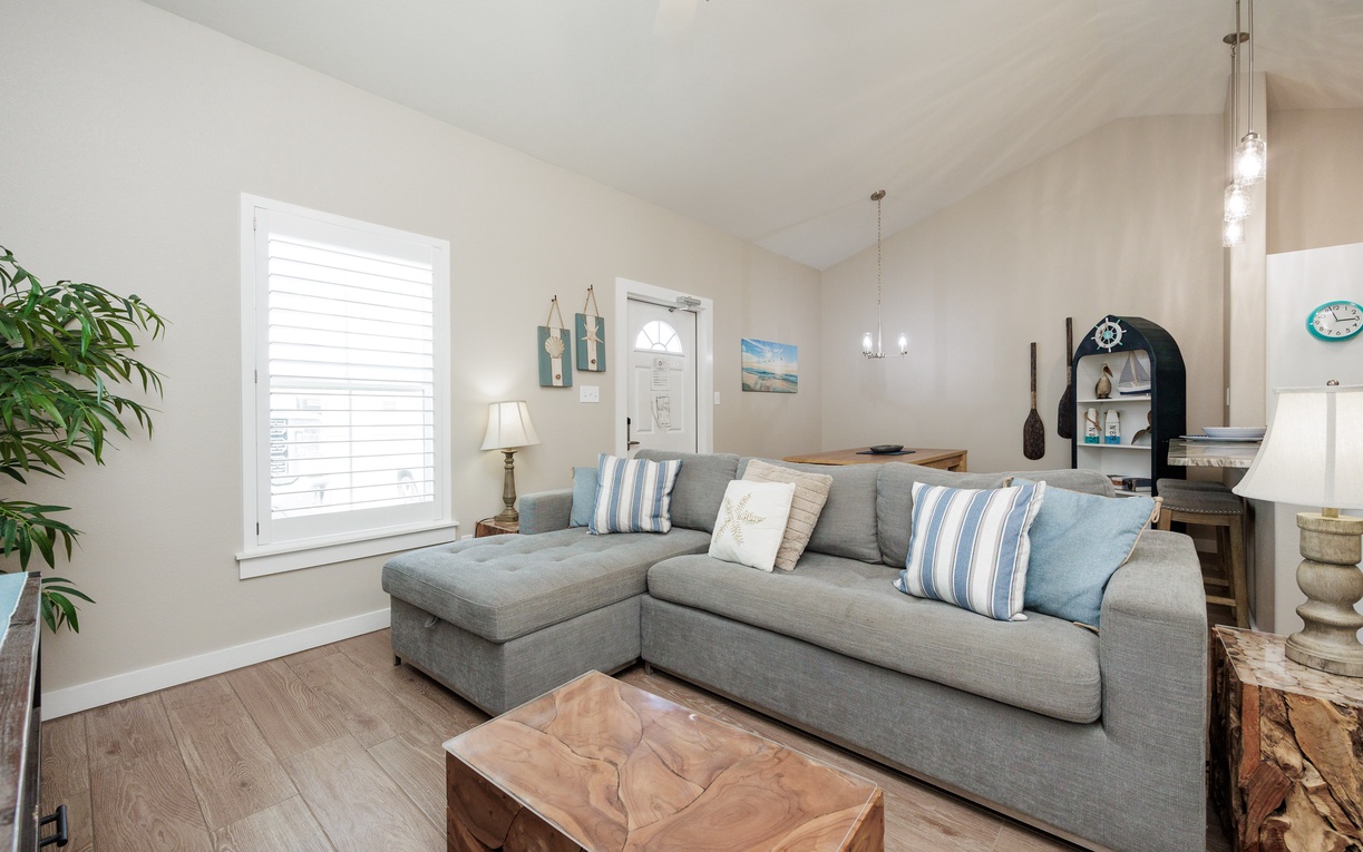 Sink into the plush sectional sleeper sofa with coastal-inspired pillows, where vaulted ceilings and warm lighting create your perfect retreat for evening relaxation.