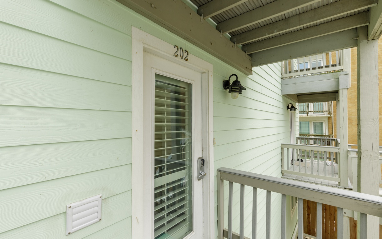 Welcome to your private entrance at unit 202, where coastal charm meets comfort on your covered balcony with charming railings.