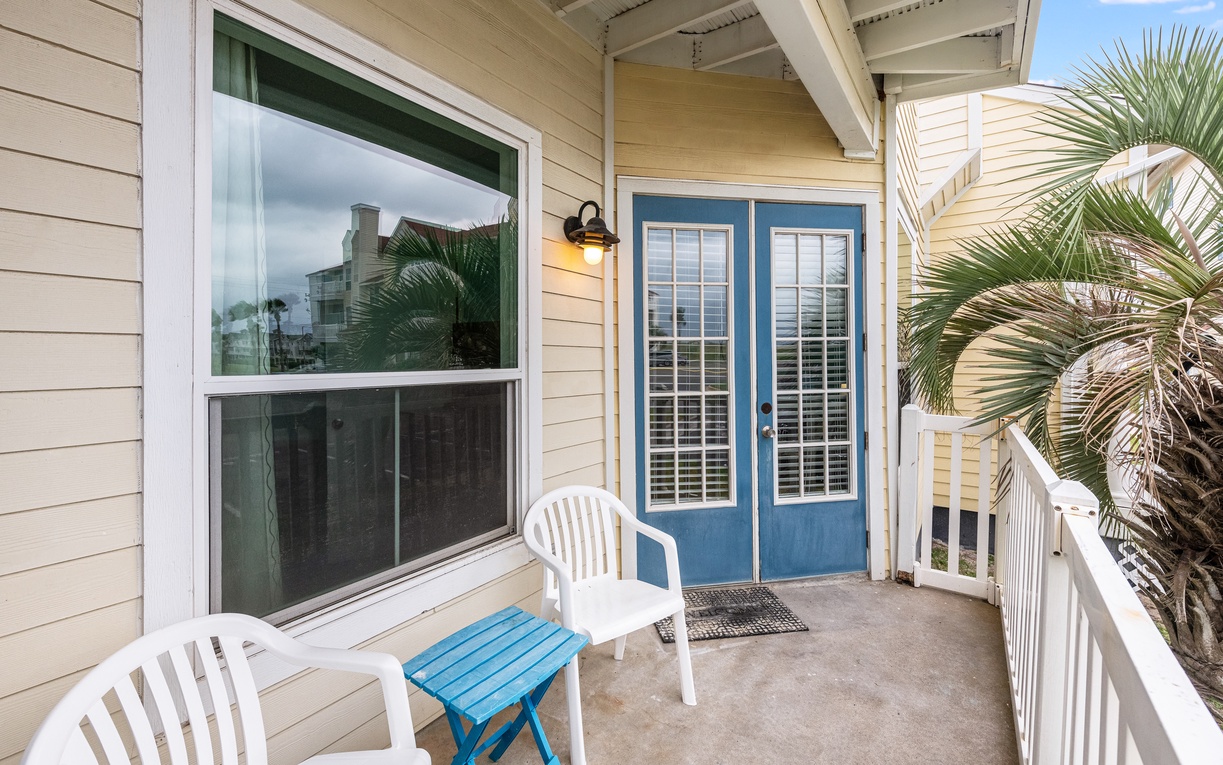 Step onto your private balcony with white chairs and blue accent table, framed by tropical palms and coastal views.