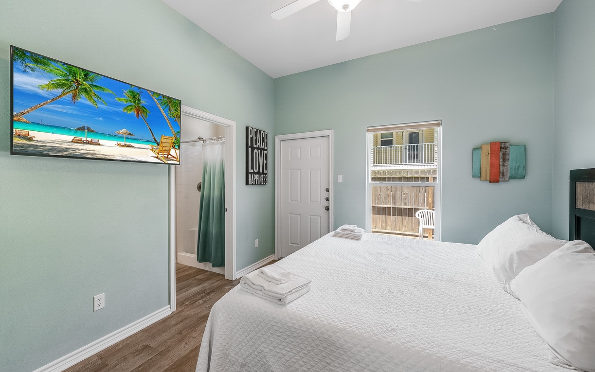 Drift into peaceful dreams in this serene bedroom with tropical beach artwork and crisp white linens that invite total relaxation.
