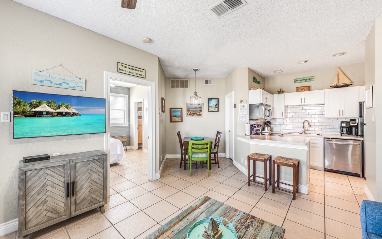 Your bright coastal-inspired space features an open kitchen with modern appliances, cozy dining nook, and beach-themed decor that instantly puts you in vacation mode.