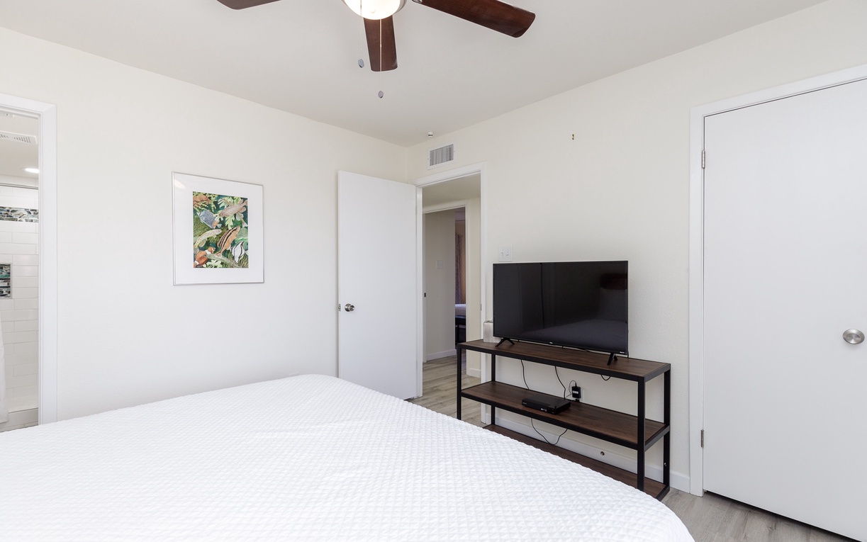 Unwind in your serene bedroom with a ceiling fan keeping you cool and a large TV for relaxation.
