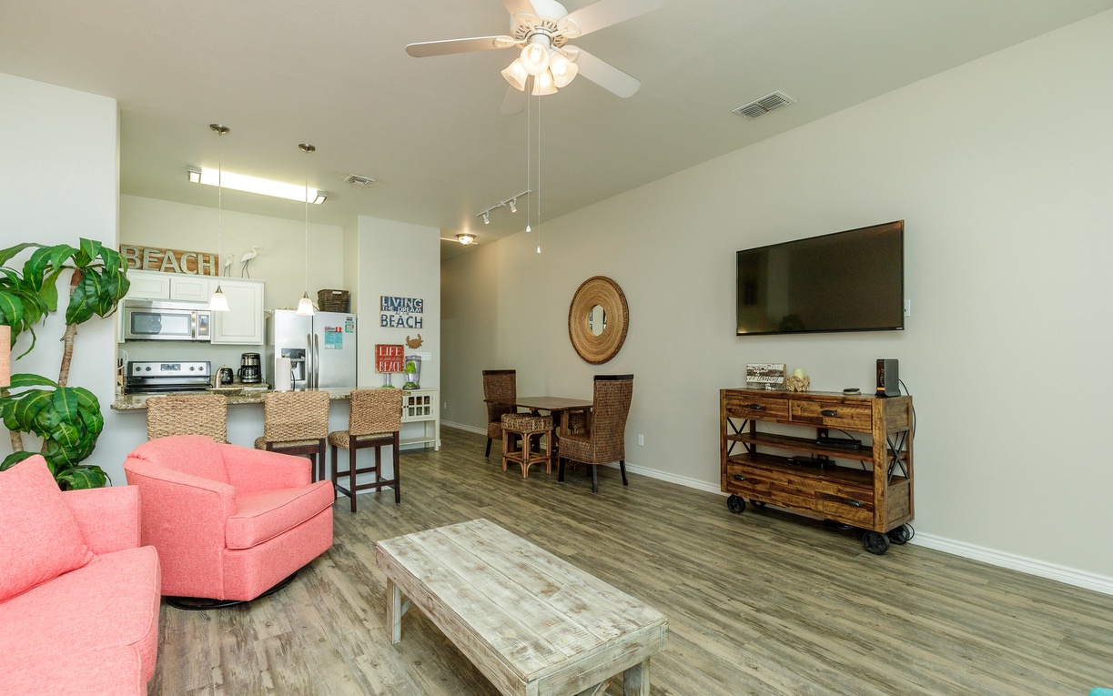 Your bright open living area features coral seating, coastal decor, and modern amenities - perfect for relaxing after beach days.