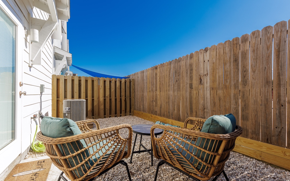 Your private outdoor sanctuary awaits with cozy rattan seating and blue shade sail protection in this charming fenced patio.