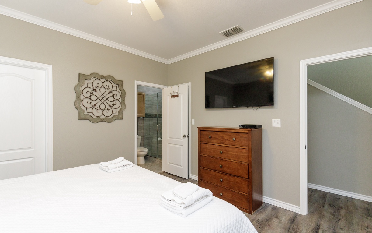 Relax in your stylish bedroom with plush linens, wall-mounted TV, and private ensuite access for ultimate convenience.