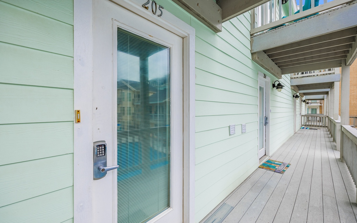 Charming mint-green coastal entrance with easy keypad access and covered walkway leading to your beachside retreat.