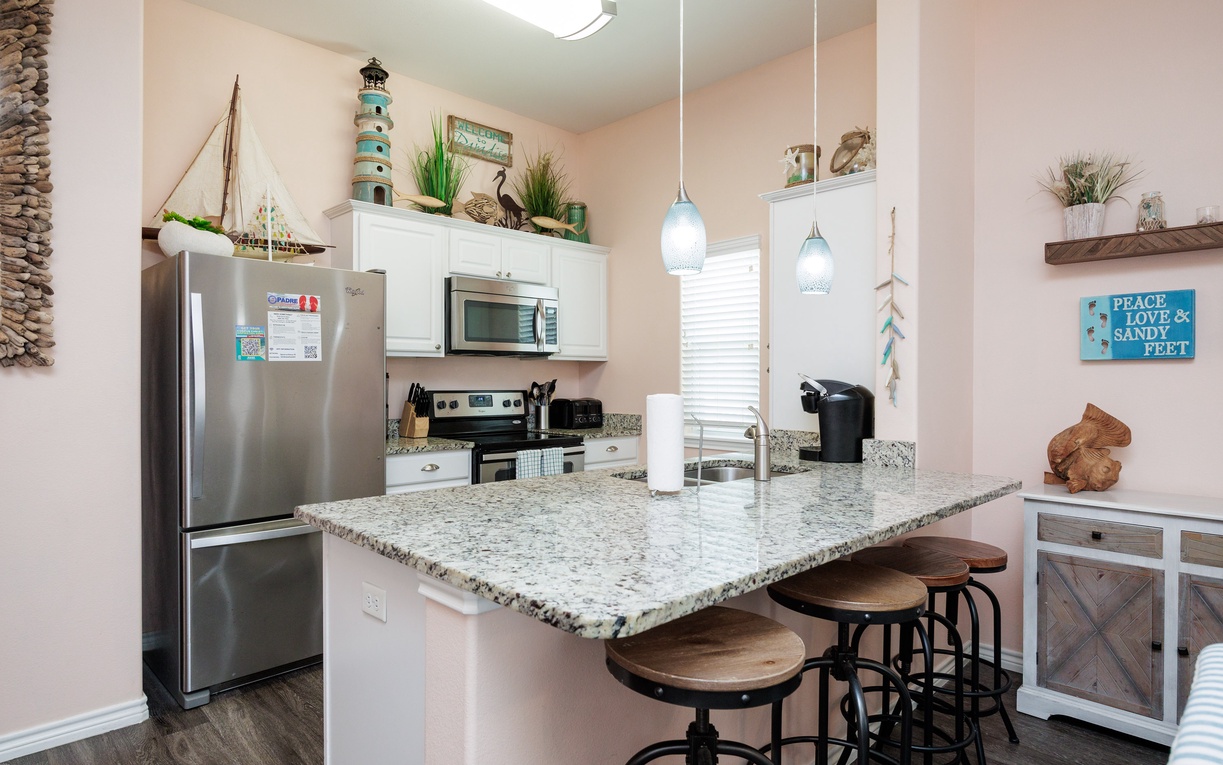 Whip up your favorite meals in this charming coastal kitchen with granite counters, modern appliances, and beach-themed touches.