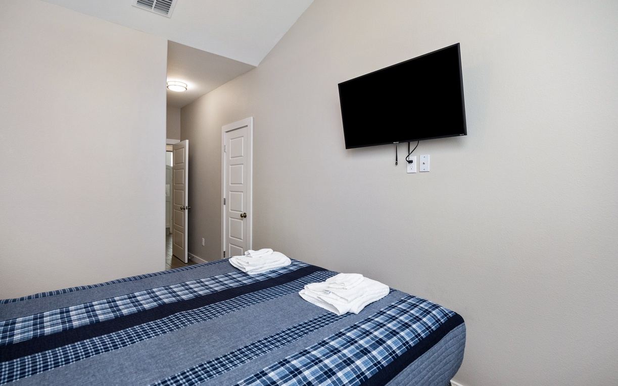 Unwind in your cozy bedroom with crisp linens and wall-mounted TV for perfect evening relaxation.