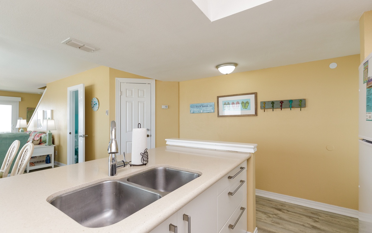 Your bright kitchen features a double-basin sink and coastal charm, perfect for preparing meals after beach adventures.