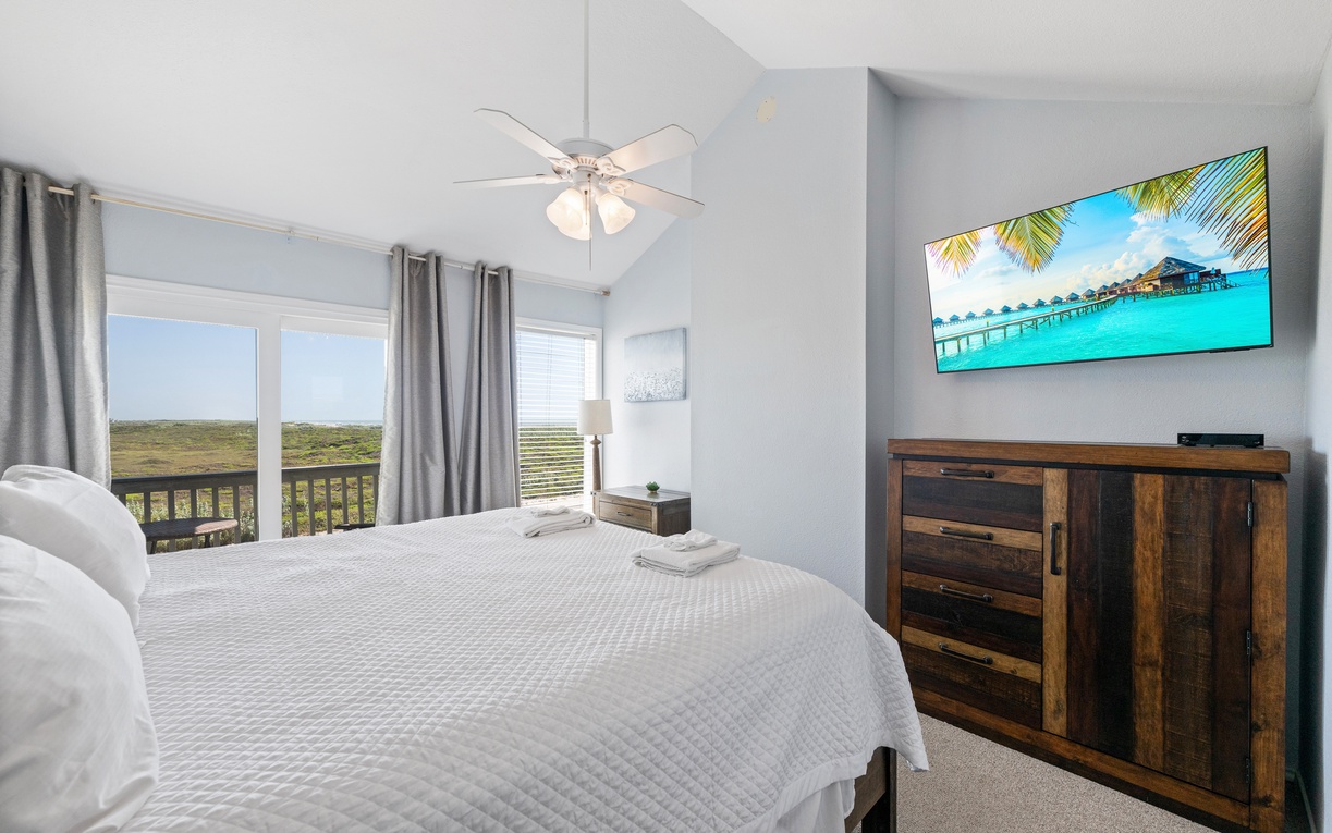 Step into your peaceful retreat, where soft bedding and calming coastal tones create the perfect escape. Natural light pours through the balcony doors, and the ceiling fan keeps your space breezy and comfortable.