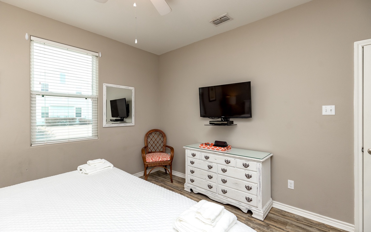 Unwind in your peaceful bedroom featuring a wall-mounted TV, elegant dresser, and cozy seating by bright windows.