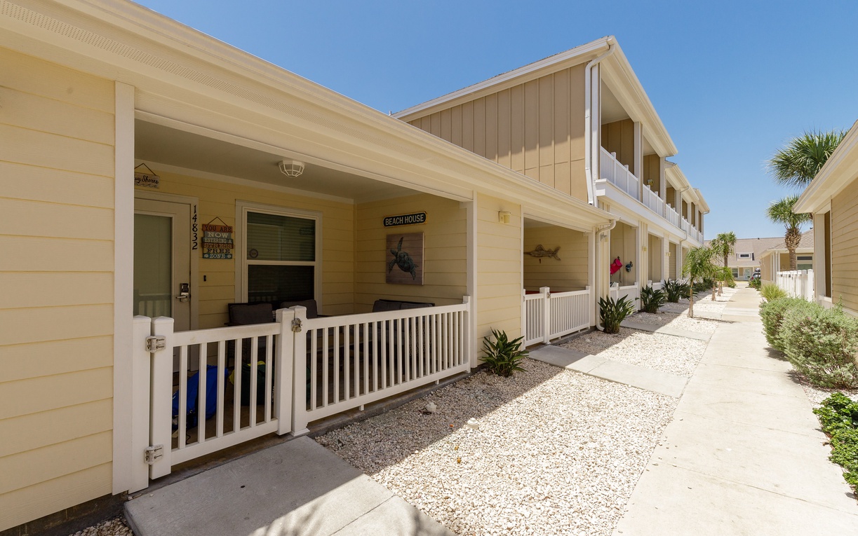 Charming beach-style cottages with covered porches and tropical landscaping create a relaxed coastal community atmosphere.