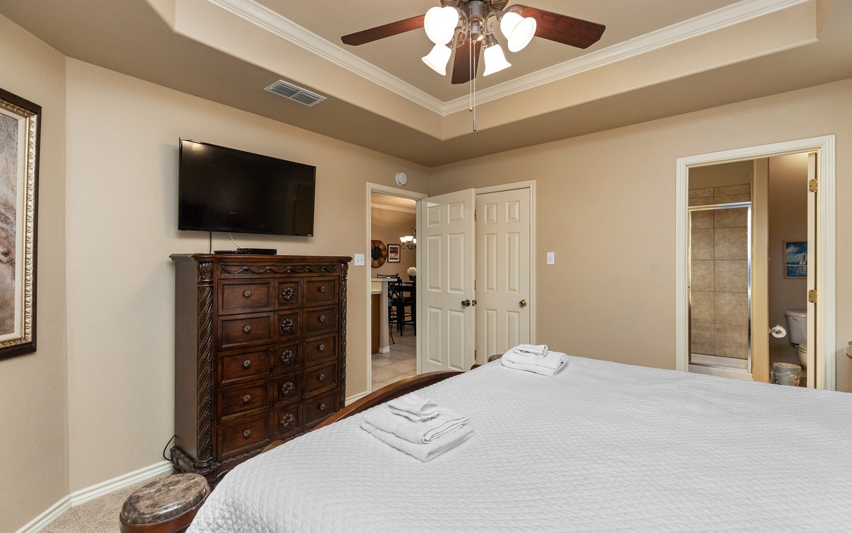 Unwind in your spacious bedroom with elegant crown molding, flat-screen TV, and plush linens awaiting your arrival.