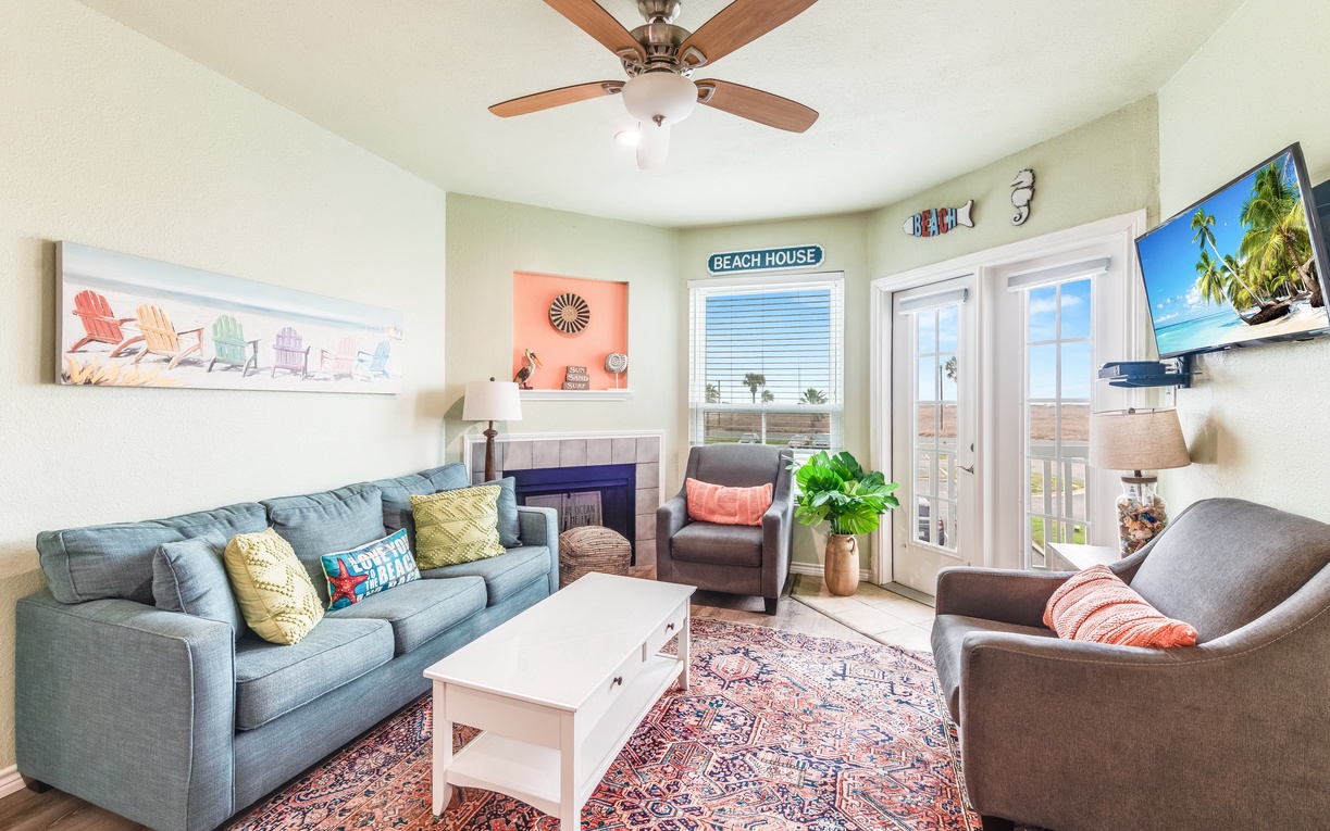Unwind in your bright living room where coastal charm meets comfort—plush seating, ceiling fan, and beach views create the perfect retreat.