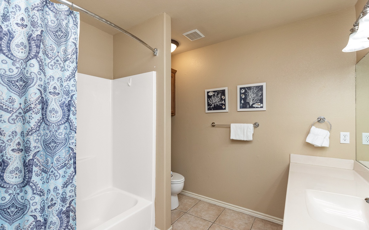Relax in your private bathroom featuring a spacious shower, elegant coastal artwork, and thoughtfully arranged towels.