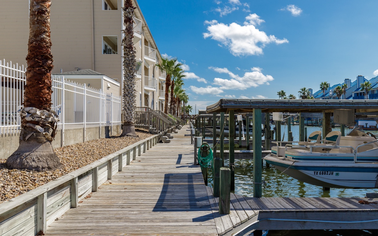 Waterfront property with private dock access and boat slips in a tropical setting with palm trees.